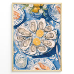Load image into Gallery viewer, Oyster platter art print plakat showing oysters and lemon slices on a blue patterned table with seafood dishes and glassware in a Golden frame.
