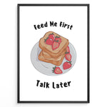 Load image into Gallery viewer, Funny kitchen poster with a plate of toast and strawberries, and the text “Feed Me First Talk Later,” framed in black on a white background.
