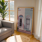 Load image into Gallery viewer, Plakat med farverige døre | Sommer og Strand Plakater | Denne plakat viser en pink og en blå dør side om side, hver i en buet dørkarm, på en farverig bygning. Perfekt til dem, der elsker unik arkitektur.
