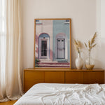 Load image into Gallery viewer, Plakat med farverige døre | Sommer og Strand Plakater | Denne plakat viser en pink og en blå dør side om side, hver i en buet dørkarm, på en farverig bygning. Perfekt til dem, der elsker unik arkitektur.
