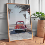 Load image into Gallery viewer, Plakat med vintage bil | Sommer og Strand Plakater | Denne plakat viser en vintage rød bil parkeret ved en strandvej med havet og palmetræer i baggrunden. Perfekt til dem, der elsker retro og strandstemning.
