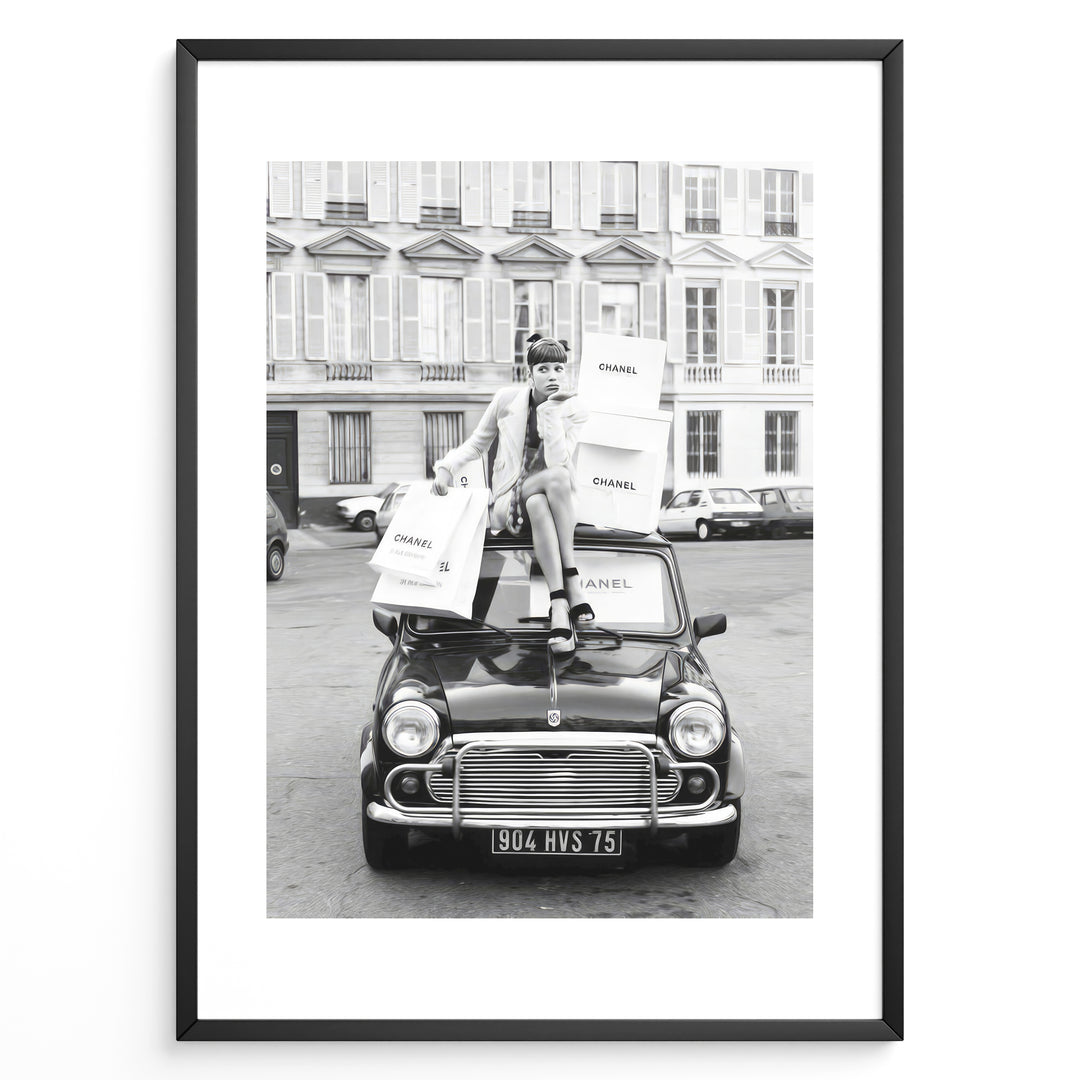 Fashion Plakat | Chanel Shopping Woman Plakaty.dk | Fashion plakat shopping i Paris | Kvinde i blazer og hæle sidder på bil med Chanel-poser foran klassisk bygning. Sort-hvid modefoto.