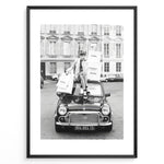 Load image into Gallery viewer, Fashion Plakat | Chanel Shopping Woman Plakaty.dk | Fashion plakat shopping i Paris | Kvinde i blazer og hæle sidder på bil med Chanel-poser foran klassisk bygning. Sort-hvid modefoto.
