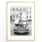 Load image into Gallery viewer, Fashion Plakat | Chanel Shopping Woman Plakaty.dk | Fashion plakat shopping i Paris | Kvinde i blazer og hæle sidder på bil med Chanel-poser foran klassisk bygning. Sort-hvid modefoto.
