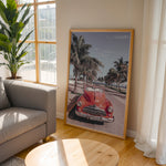 Load image into Gallery viewer, Plakat med vintage rød bil | Sommer og Strand Plakater | Denne plakat viser en klassisk rød cabriolet parkeret på en gade med palmer ved stranden. Perfekt til retro- og strandelskere.
