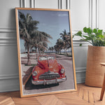 Load image into Gallery viewer, Plakat med vintage rød bil | Sommer og Strand Plakater | Denne plakat viser en klassisk rød cabriolet parkeret på en gade med palmer ved stranden. Perfekt til retro- og strandelskere.
