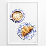 Load image into Gallery viewer, Art print of a cappuccino and croissant on blue patterned plates — French café-style kitchen wall décor.
