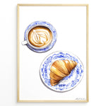 Load image into Gallery viewer, Art print of a cappuccino and croissant on blue patterned plates — French café-style kitchen wall décor.
