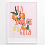 Load image into Gallery viewer, Stylish La Dolce Vita poster with oranges, green leaves, and champagne glasses on a pink background, framed as Italian-inspired wall art.
