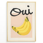 Load image into Gallery viewer, Modern art poster featuring the word “Oui” in bold black text above a bunch of yellow bananas on a soft pink background, framed as French kitchen wall décor.
