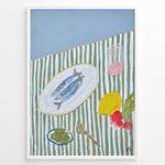 Load image into Gallery viewer, Mediterranean still life poster with fish on a white plate, lemon, radishes, olives, and a pink drink on a green and white striped tablecloth, framed as kitchen wall art.
