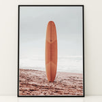 Load image into Gallery viewer, Plakat med surfbræt på stranden | Sommer og Strand Plakater | Denne plakat viser et surfbræt stående oprejst på en rolig sandstrand med havet i baggrunden. Perfekt til strand- og surfentusiaster.
