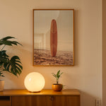 Load image into Gallery viewer, Plakat med surfbræt på stranden | Sommer og Strand Plakater | Denne plakat viser et surfbræt stående oprejst på en rolig sandstrand med havet i baggrunden. Perfekt til strand- og surfentusiaster.
