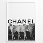 Load image into Gallery viewer, Fashion Plakat | CHANEL Newspaper Bench – Fashion Art Poster Plakaty.dk | Black and white fashion poster of four women sitting on a bench reading newspapers, with the bold text &quot;CHANEL&quot; across the top half of the image.
