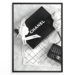 Load image into Gallery viewer, Fashion Plakat | Chanel Gift Box &amp; Handbag Flatlay Wall Art Plakaty.dk | Black and white flatlay of a Chanel gift box with ribbon, camellia flowers, and a quilted Chanel handbag on a soft surface.
