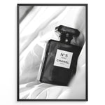 Load image into Gallery viewer, Fashion Plakat | Chanel No. 5 L’Eau Perfume Bottle – Black and White Fashion Photography Plakaty.dk | Black and white photo of a Chanel No. 5 L’Eau perfume bottle resting on a bed of soft white fabric.
