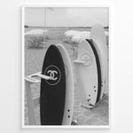 Load image into Gallery viewer, Fashion Plakat | Chanel Surfboards on the Beach – Luxury Meets Coastal Lifestyle in Black and White Plakaty.dk | Black and white photo of Chanel and J12 Yacht Club surfboards on a sandy beach with umbrellas and lounge chairs in the background
