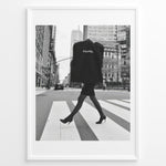 Load image into Gallery viewer, Fashion Plakat | Chic Chanel Street Style Fashion Print Plakaty.dk | Black and white photo of a stylish woman in heels crossing a city street while carrying a Chanel garment bag, framed as wall art.
