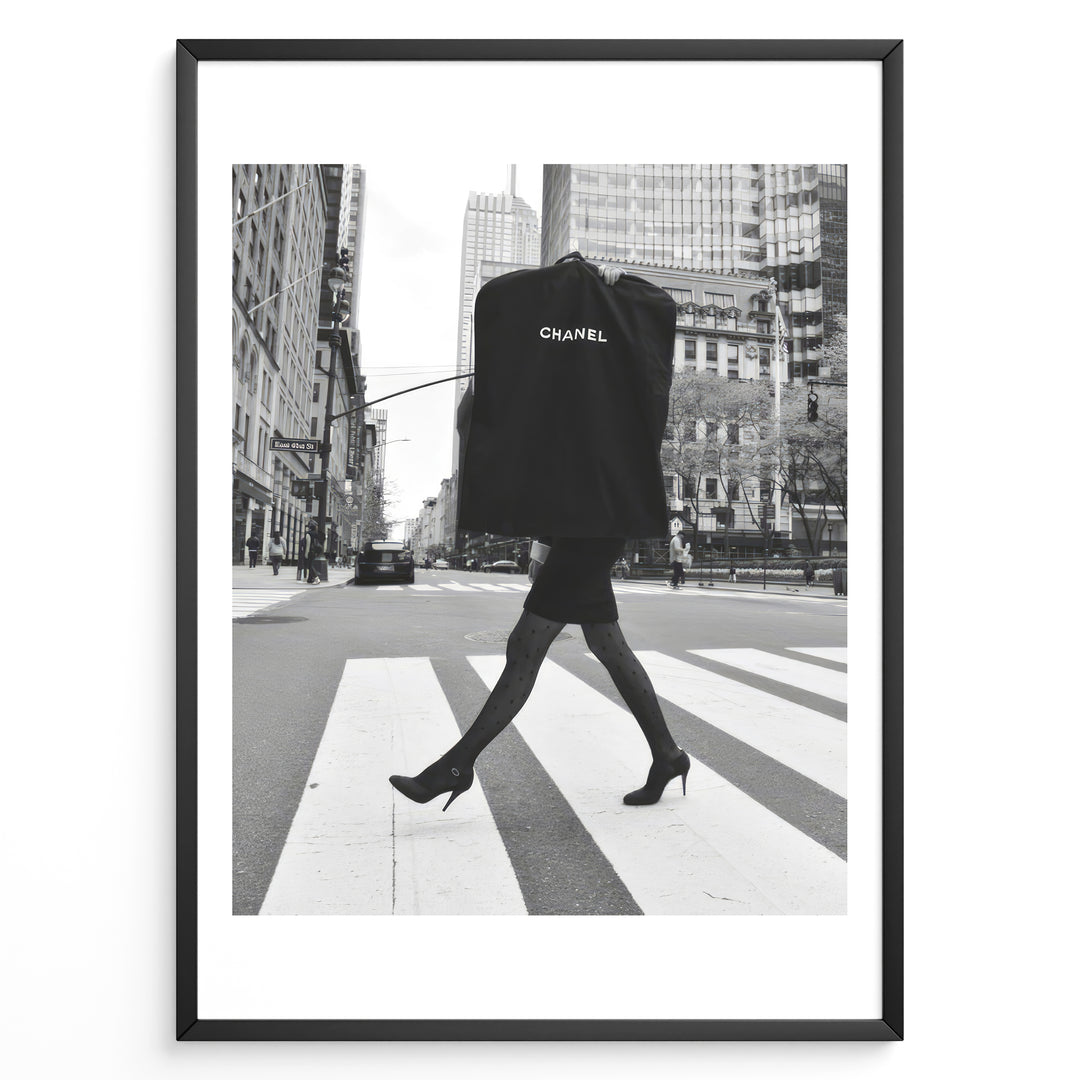 Fashion Plakat | Chic Chanel Street Style Fashion Print Plakaty.dk | Black and white photo of a stylish woman in heels crossing a city street while carrying a Chanel garment bag, framed as wall art.