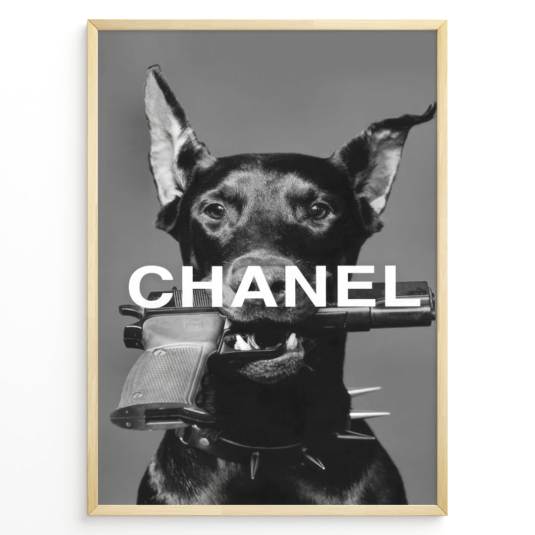 Fashion Plakat | Edgy Chanel-Inspired Art Featuring Dog with Gun Plakaty.dk | Black dog with spiked collar holding a handgun in its mouth, with the word "CHANEL" overlaid in bold white text.