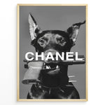 Load image into Gallery viewer, Fashion Plakat | Edgy Chanel-Inspired Art Featuring Dog with Gun Plakaty.dk | Black dog with spiked collar holding a handgun in its mouth, with the word &quot;CHANEL&quot; overlaid in bold white text.
