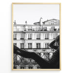 Load image into Gallery viewer, Fashion Plakat | Elegant Woman Relaxing on Parisian Balcony – Black and White Photography Plakaty.dk | Black and white photo of a woman relaxing on a Parisian balcony with classic building architecture in the background
