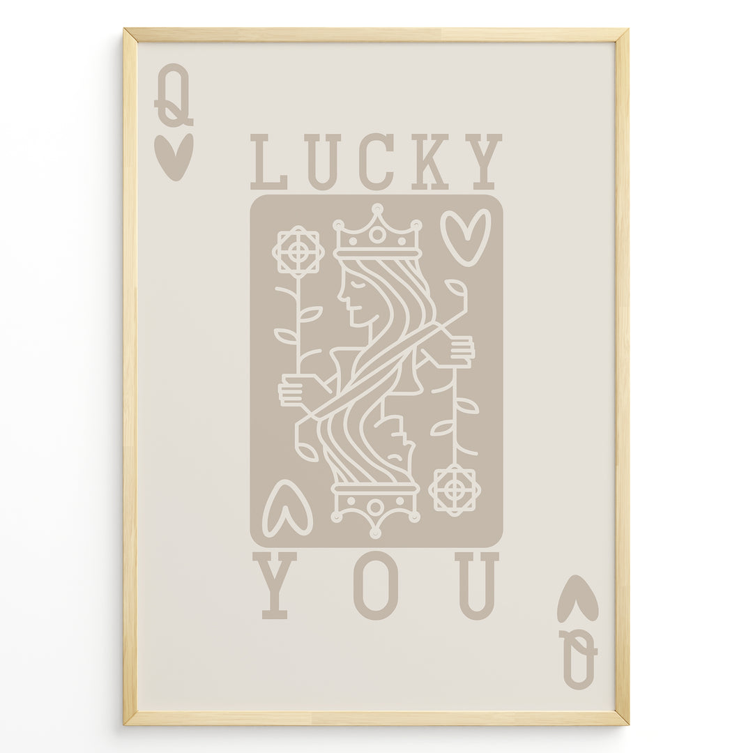 Framed minimalist “Lucky You” poster featuring Queen of Hearts playing card design in beige tones on a neutral background.