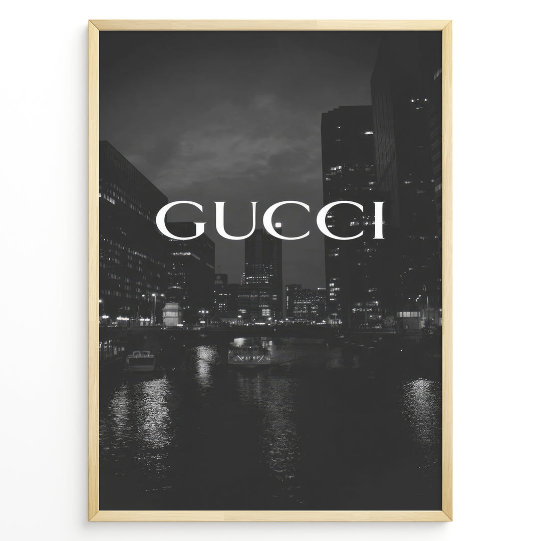 Fashion Plakat | Gucci Cityscape Black & White Fashion Poster Plakaty.dk | Black and white poster with the Gucci logo over a night cityscape featuring tall buildings and water reflections.