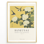 Load image into Gallery viewer, Japanske plakater | Japanese woodblock print of white trumpet lilies with green leaves and two sparrows flying against a yellow background, based on Hokusai’s  floral artwork.
