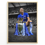 Load image into Gallery viewer, John Terry im Chelsea-Trikot mit der Premier-League-Trophäe vor den Chelsea-Fans. Die ikonischen blauen Farben heben sich vom schwarz-weißen Stadionhintergrund ab.
