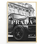 Load image into Gallery viewer, Fashion Plakat | Luxury Lifestyle: Mercedes G-Wagon x Prada Milano Wall Art Plakaty.dk | Black and white framed photo of a Mercedes G-Wagon with Prada Milano text overlay, parked in front of ornate historic buildings.
