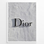 Load image into Gallery viewer, Fashion Plakat | Minimalist Dior Wall Sign – Timeless Fashion Statement Plakaty.dk | Minimalist black Dior logo mounted on a textured white wall, casting a soft shadow and evoking luxury and elegance.
