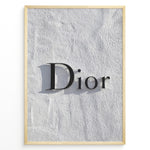 Load image into Gallery viewer, Fashion Plakat | Minimalist Dior Wall Sign – Timeless Fashion Statement Plakaty.dk | Minimalist black Dior logo mounted on a textured white wall, casting a soft shadow and evoking luxury and elegance.
