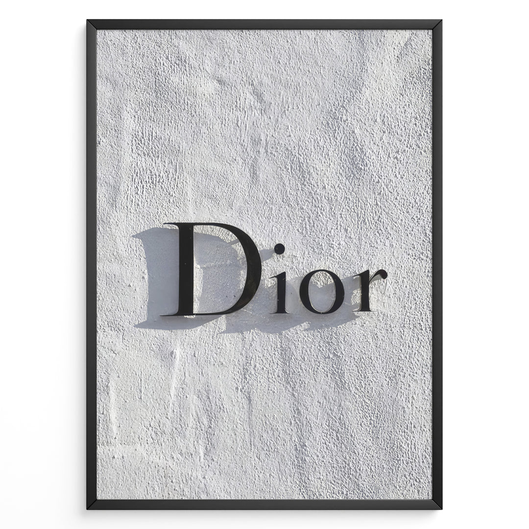 Fashion Plakat | Minimalist Dior Wall Sign – Timeless Fashion Statement Plakaty.dk | Minimalist black Dior logo mounted on a textured white wall, casting a soft shadow and evoking luxury and elegance.