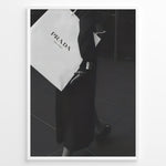 Load image into Gallery viewer, Fashion Plakat | Prada Shopping Bag Fashion Photography Wall Art Plakaty.dk | Black and white photo of a person holding a large Prada Milano shopping bag, dressed in elegant dark clothing.
