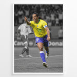 Load image into Gallery viewer, Ronaldinho wearing the iconic yellow Brazil football jersey with number 10 while celebrating on the pitch. A black and white background highlights the Brazilian colors.
