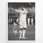 Load image into Gallery viewer, Framed plakat of Vinícius Jr. in a Real Madrid kit doing an eye-cover celebration, with a black and white background and printed signature
