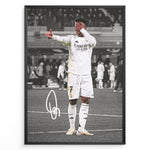 Load image into Gallery viewer, Framed plakat of Vinícius Jr. in a Real Madrid kit doing an eye-cover celebration, with a black and white background and printed signature
