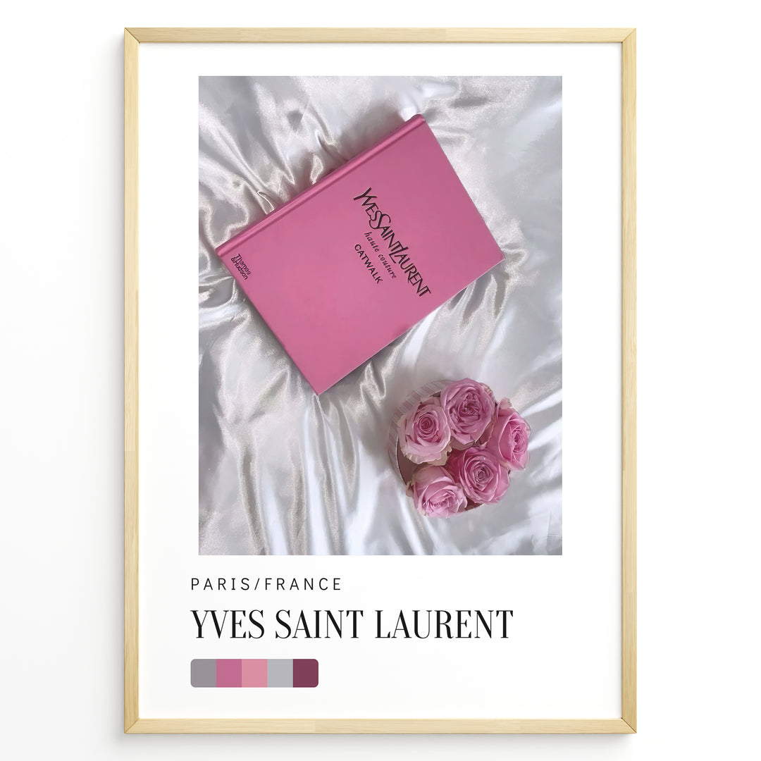 Fashion Plakat | Yves Saint Laurent Pink Book on Silk – Paris Fashion Decor Plakaty.dk | Yves Saint Laurent pink Catwalk book placed on white silk fabric with pink roses beside it, representing Parisian luxury and soft elegance.