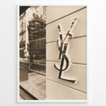 Load image into Gallery viewer, Fashion Plakat | Yves Saint Laurent Sepia Storefront – Vintage Luxury Wall Art Plakaty.dk | Sepia-toned photo of the Yves Saint Laurent storefront with a prominent YSL logo on a white wall and reflections of the cityscape in the background.
