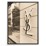 Load image into Gallery viewer, Fashion Plakat | Yves Saint Laurent Sepia Storefront – Vintage Luxury Wall Art Plakaty.dk | Sepia-toned photo of the Yves Saint Laurent storefront with a prominent YSL logo on a white wall and reflections of the cityscape in the background.
